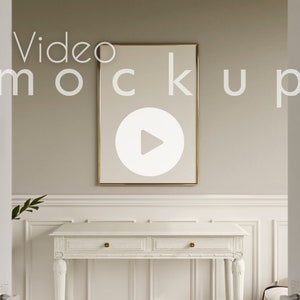 Könnte beinhalten: Ein weißer Konsolentisch mit zwei Schubladen und goldenen Akzenten steht in einem Raum mit einem goldgerahmten Bild an der Wand. Das Bild hat ein Play-Button-Symbol in der Mitte. Der Text "Video mockup" steht über dem Bild.