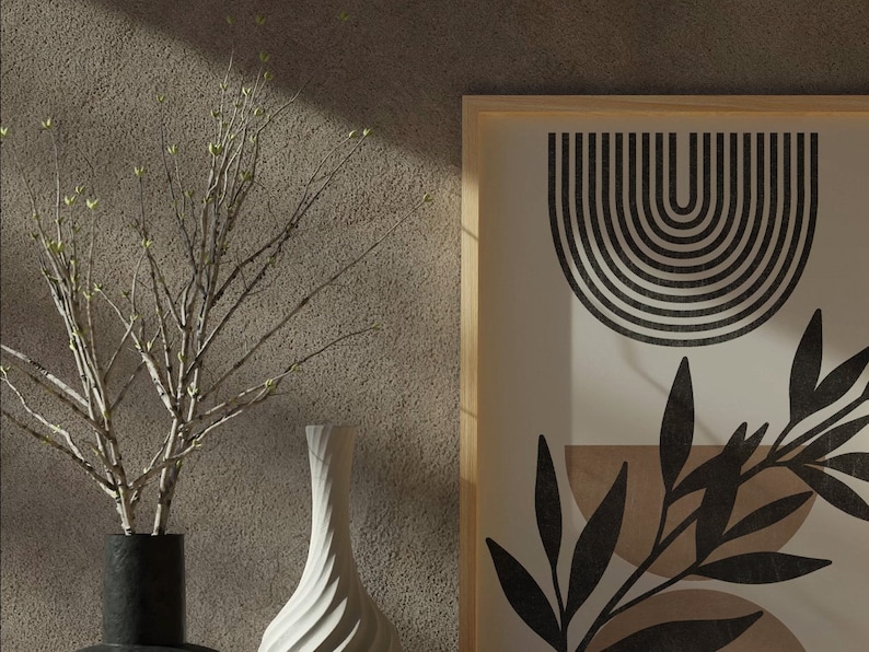 Op de afbeelding: Een ingelijst print met een zwart-wit abstract ontwerp met een reeks gebogen lijnen en een gestileerd blad. De print is op een cr&egrave;mekleurige achtergrond en is ingelijst in natuurlijk hout.