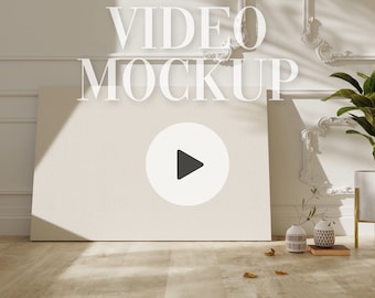 May include: A white canvas mockup with a play button icon in a circle, set against a white wall with ornate molding. The text "VIDEO MOCKUP" is displayed above the canvas.
