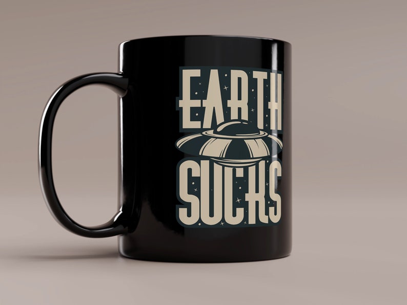 May include: Black ceramic mug with a white graphic of a UFO and the text "EARTH SUCKS".