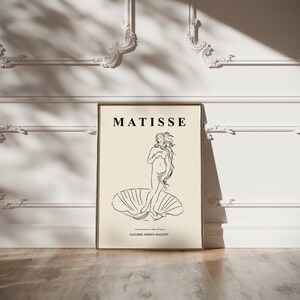 May include: A black and white line drawing of a woman standing on a shell. The drawing is titled "MATISSE" and is from "GALERIE ADRIEN MAEGHT".