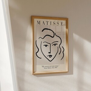 May include: A framed black and white line drawing of a woman's face with the text "MATISSE" at the top and the quote "My curves are not crazy." - Henri Matisse, June, 1947 at the bottom.