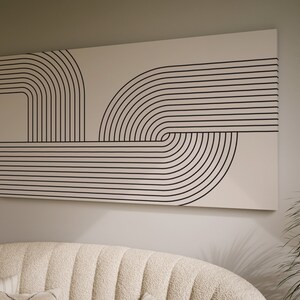 May include: Abstract wall art featuring a black and white geometric design of curved lines and stripes on a cream background.