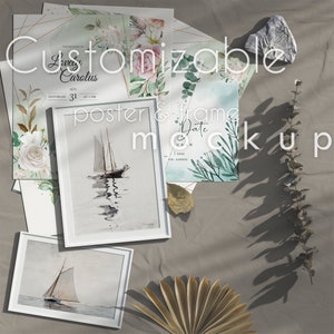 May include: A customizable poster and frame mockup with a white background. The mockup features a white frame with a watercolor painting of a sailboat on the water, a white frame with a blank space for a photo, a floral wedding invitation, and a small card with the text "Date" on it. The mockup is surrounded by dried leaves and branches.