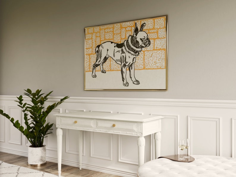 May include: A black and white illustration of a French Bulldog wearing a collar, set against a yellow and white patterned background. The illustration is framed in a gold frame and hangs on a light gray wall above a white console table.