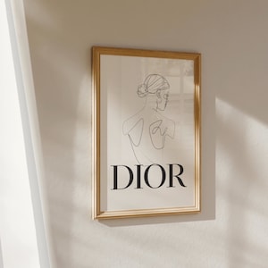May include: A framed print with a line drawing of a woman's back with the word "DIOR" printed below the drawing.