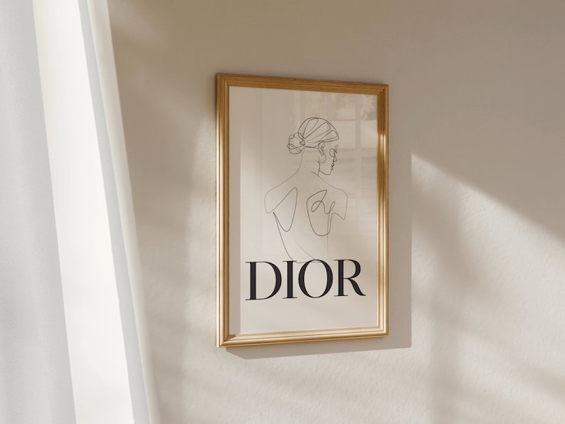 May include: A framed print with a line drawing of a woman's back with the word "DIOR" printed below the drawing.