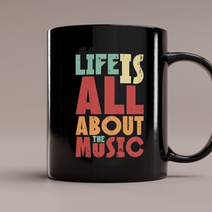 May include: Black ceramic coffee mug with a white design that reads "Life is all about the music" in a vintage style font with colorful accents.