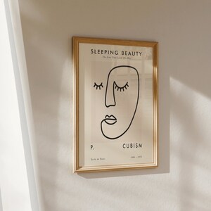 May include: A framed print with a black and white line drawing of a face with the text "SLEEPING BEAUTY The Love That Lasts The Way" and "CUBISM 1908 - 1917" and "P. Ecole de Paris" in the bottom right corner.