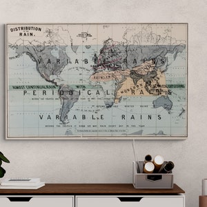 May include: A framed vintage world map depicting the distribution of rain, with text labels such as "Variable Rains" and "Almost Continual Rain." The map is in a white frame and hangs on a white wall above a wooden shelf.