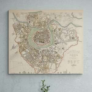 May include: An antique map of Vienna, Austria, printed on cream-colored paper with brown and green ink. The map shows the city's streets, buildings, and landmarks. The title "VIENNA" is printed in the lower right corner.