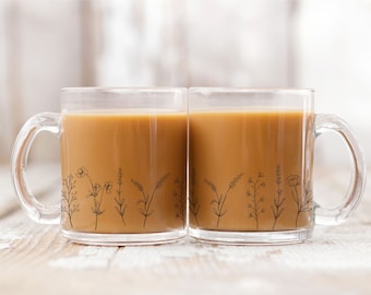 May include: Two clear glass mugs with black floral designs on the side, filled with coffee.