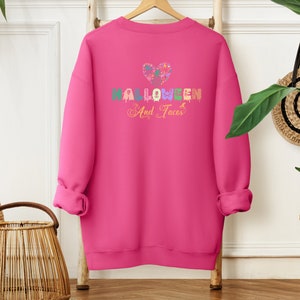 Funny I Love Halloween and Tacos Sweatshirt with a design in vibrant colors. Shirts are available in various colors.