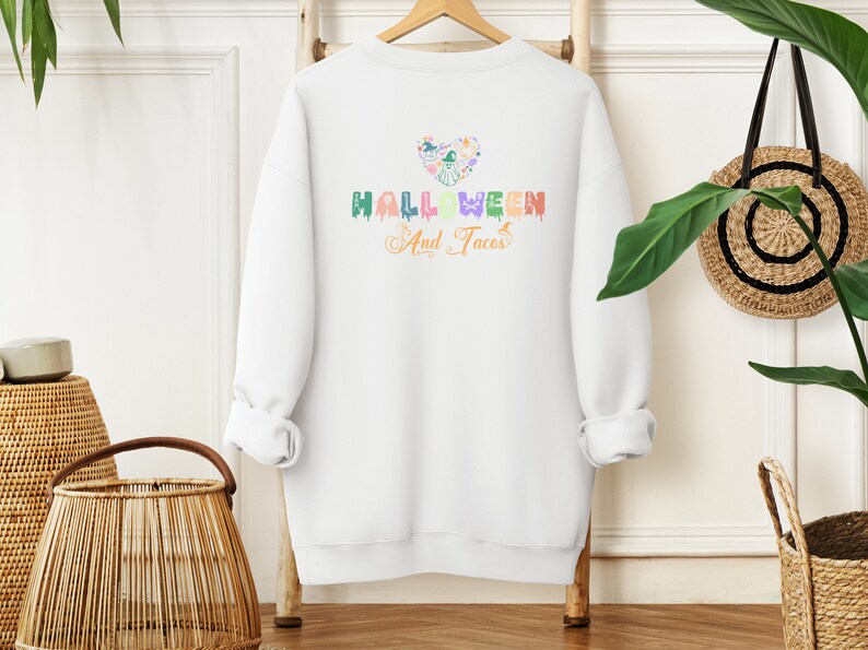 Funny I Love Halloween and Tacos Sweatshirt with a design in vibrant colors. Shirts are available in various colors.