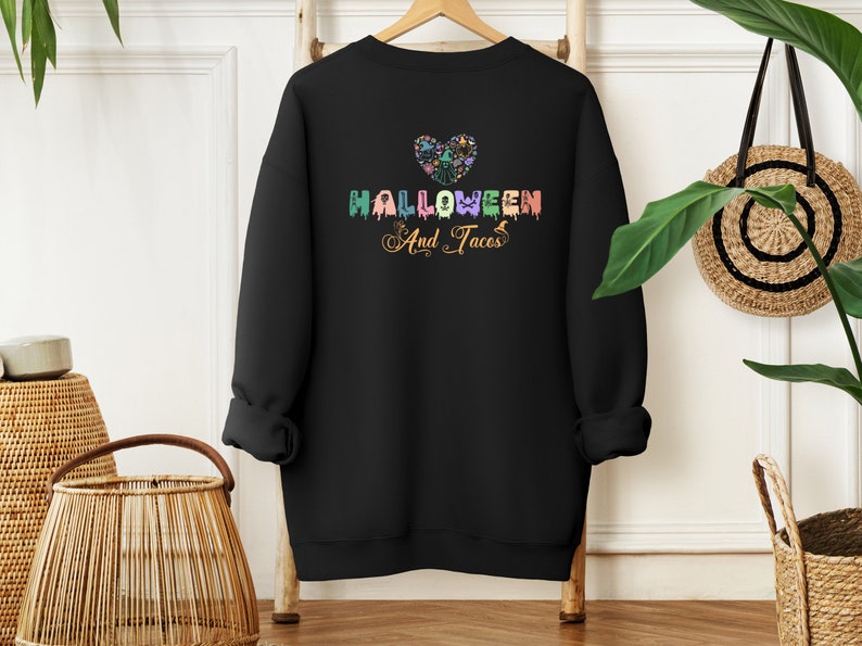 Funny I Love Halloween and Tacos Sweatshirt with a design in vibrant colors. Shirts are available in various colors.