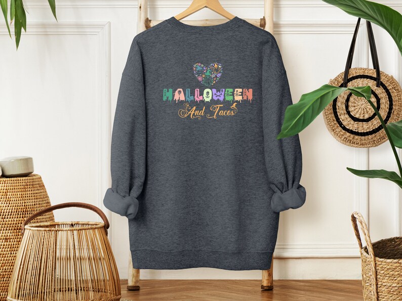 Funny I Love Halloween and Tacos Sweatshirt with a design in vibrant colors. Shirts are available in various colors.