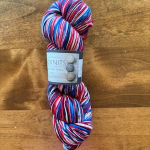 May include: A skein of hand-dyed yarn in red, white, and blue colors. The yarn is called "CKNITS" and is hand-dyed from "The Wools".