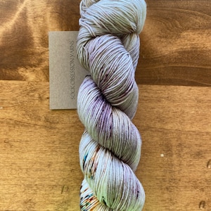 May include: A skein of grey yarn with purple, blue and orange speckles. The yarn is labelled "Sock Obsession Yarns".