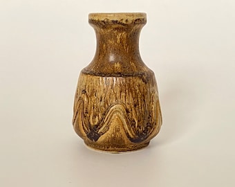 May include: A small, brown ceramic vase with a textured, wavy design. The vase has a narrow neck and a wide, rounded base.