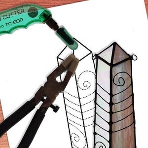May include: A stained glass pattern for a wire-wrapped crystal point. The pattern is designed for a 2.0 inch by 6.25 inch piece of glass. The pattern includes a swirl design and a chevron pattern.