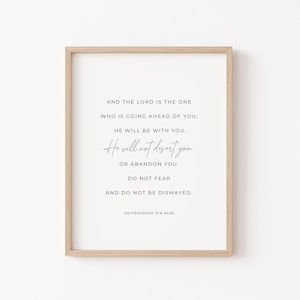 May include: A framed print with a white background and black text. The text reads: "And the Lord is the one who is going ahead of you; He will be with you. He will not desert you or abandon you. Do not fear and do not be dismayed. Deuteronomy 31:8 NASB"