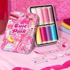 May include: A pink sewing kit with the text "Cute and Pink" and "Girl Power" is open, revealing spools of thread, a measuring tape, pins, and other sewing supplies. The kit is decorated with various pink and white graphics.