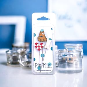 May include: A pack of three colourful sewing pins with a dog, heart, and bone design. The pack is labelled "Pin-Mini" and "JustAnotherButtonsCompany.com".