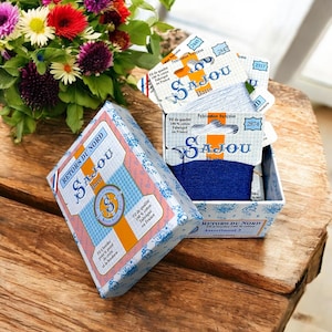 May include: A blue box with a white and yellow label that says "Retors du Nord Sajou Paris" and a smaller box inside with a spool of blue embroidery floss. The label on the smaller box says "Sajou Paris" and "Fabrication Française".