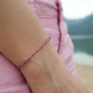 Op de afbeelding: Een delicate armband gemaakt van kleine, roze edelsteen kralen. De armband wordt gedragen op iemands pols.