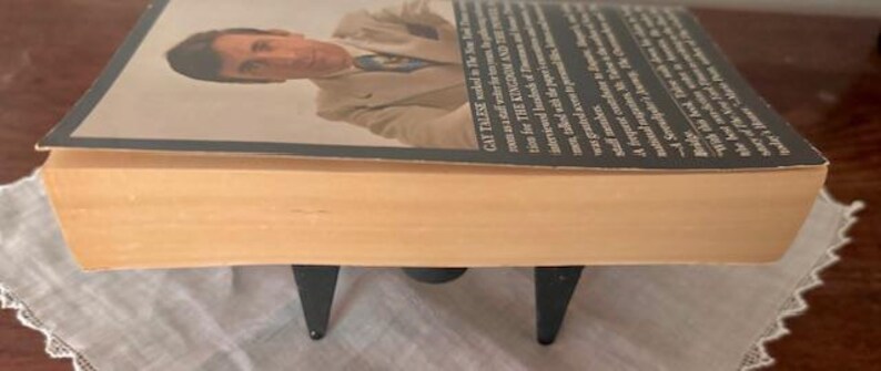 Puede incluir: Un libro de bolsillo con una columna vertebral de color canela y una cubierta negra. La cubierta presenta una foto de un hombre con traje y corbata. El texto de la cubierta dice "Gay Talese" y "The Kingdom and the Power".