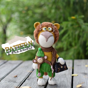Puede incluir: Un león de crochet con gafas y una bufanda marrón sostiene un mono de crochet con un sombrero verde y lleva un bolso marrón. La palabra "PATTERN" está escrita en un trozo de papel en el fondo.