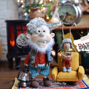 May include: Two crocheted amigurumi toys, a gnome and a mouse, sitting on a yellow armchair. The gnome is wearing a red and blue outfit and holding a book. The mouse is wearing a red and brown outfit and holding a book. The word "PATTERN" is written on a piece of paper in the background.
