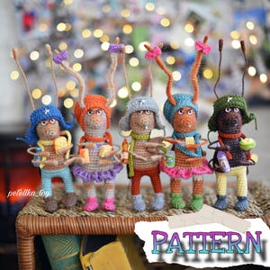 May include: Five crocheted amigurumi figures of ants wearing hats and carrying items. The ants are brown, orange, red, blue, and green. The hats are blue, orange, red, and green. The items are a piece of cheese, a bottle of juice, a piece of fruit, and a bottle of liquid. The word "PATTERN" is written on a torn piece of paper in the foreground.