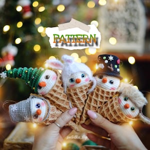 May include: Four crocheted snowman ornaments in waffle cone holders. The snowmen are wearing hats and scarves. The snowmen are in a person's hands. The image has the text "PATTERN" on it.