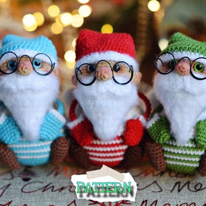 May include: Three crocheted Santa Claus ornaments, each wearing a different colored hat: blue, red, and green. Each Santa has a white beard and black glasses.