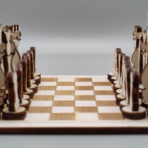 以下が含まれることがあります： 木製のチェスセットで、すべての駒が小さな木製ボードにセットされています。駒は薄い茶色の木でできており、古典的なチェスの駒の形をしています。