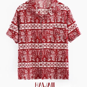 May include: A red short-sleeved button-down shirt with a white elephant print. The shirt has a collar and a pocket on the left side. The text "HAWAII" is printed on the bottom of the shirt.