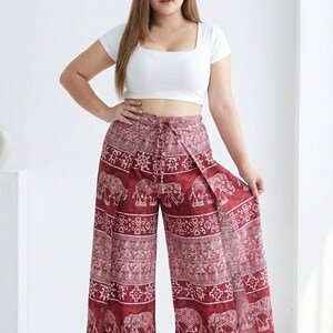 Puede incluir: Pantalones palazzo de pernera ancha con estampado de elefantes en burdeos y blanco. Los pantalones tienen cintura con cordón y diseño de abertura frontal. La modelo lleva un top corto blanco.