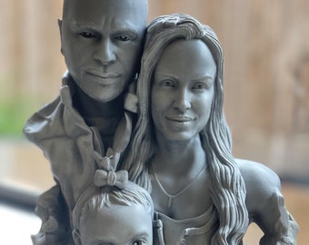 Puede incluir: Una escultura de busto familiar gris que representa a un hombre, una mujer y un niño. La escultura es una representación detallada de la familia, con el niño en primer plano. La mujer tiene el pelo largo y el niño tiene un lazo en el pelo.