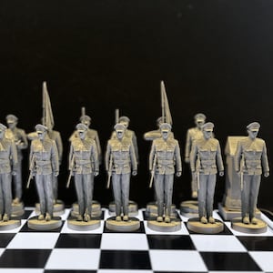 May include: A set of gray plastic toy soldiers standing on a black and white checkerboard. The soldiers are all wearing uniforms and hats, and some are holding rifles.