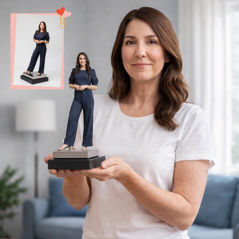 May include: A 3D-printed figurine of a person in a navy blue jumpsuit, standing on a tiered black and gray base. The figurine is held by a person wearing a white t-shirt. A smaller image of the figurine is in the upper left corner.