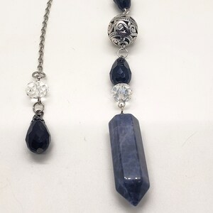May include: A silver chain with a blue crystal point pendant, black crystal beads, and a silver bead with an ornate design.