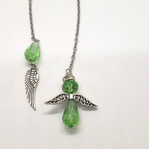 May include: A silver chain with a green crystal angel charm and a single green crystal wing charm.