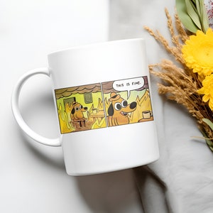 May include: White ceramic mug featuring a meme image of a dog sitting in a burning house, saying "This is fine."