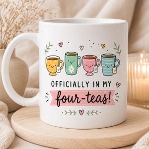 May include: White ceramic mug with a handle, featuring four cartoon tea cups in yellow, green, pink, and blue. The mug has the text "OFFICIALLY IN MY four-teas!" in black script on a pink banner, with decorative hearts and leaves.