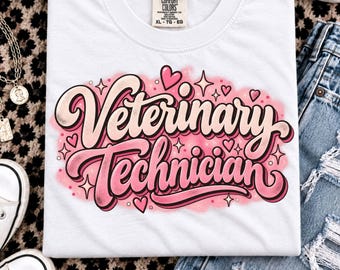 May include: A white short-sleeve t-shirt featuring the text Veterinary Technician in a pink and cream cursive font. The design is surrounded by pink airbrushed accents, small hearts, and star shapes. The shirt has a Comfort Colors brand label.