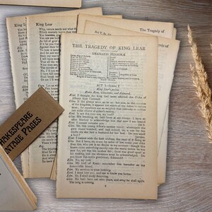 May include: Vintage pages from Shakespeare's "King Lear" are displayed on a wooden surface. The pages are aged with visible text, and a brown tag reads "Shakespeare Vintage Pages." A sprig of dried wheat adds a rustic touch.