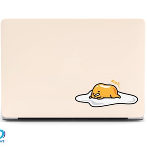May include: A light beige laptop with a cartoon graphic of a fried egg with the word "meh..." in a speech bubble. The egg yolk is yellow, and the egg white is white with a black outline.