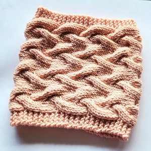 Peut inclure: Un col roulé en tricot doux de couleur rose avec un motif en câble.