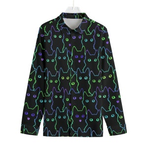 May include: A black long-sleeved button-up shirt with a neon green, blue, and purple cat print.